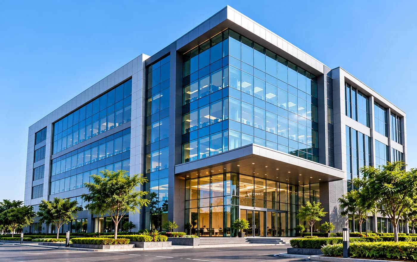 A modern glass corporate office building against a clear sky